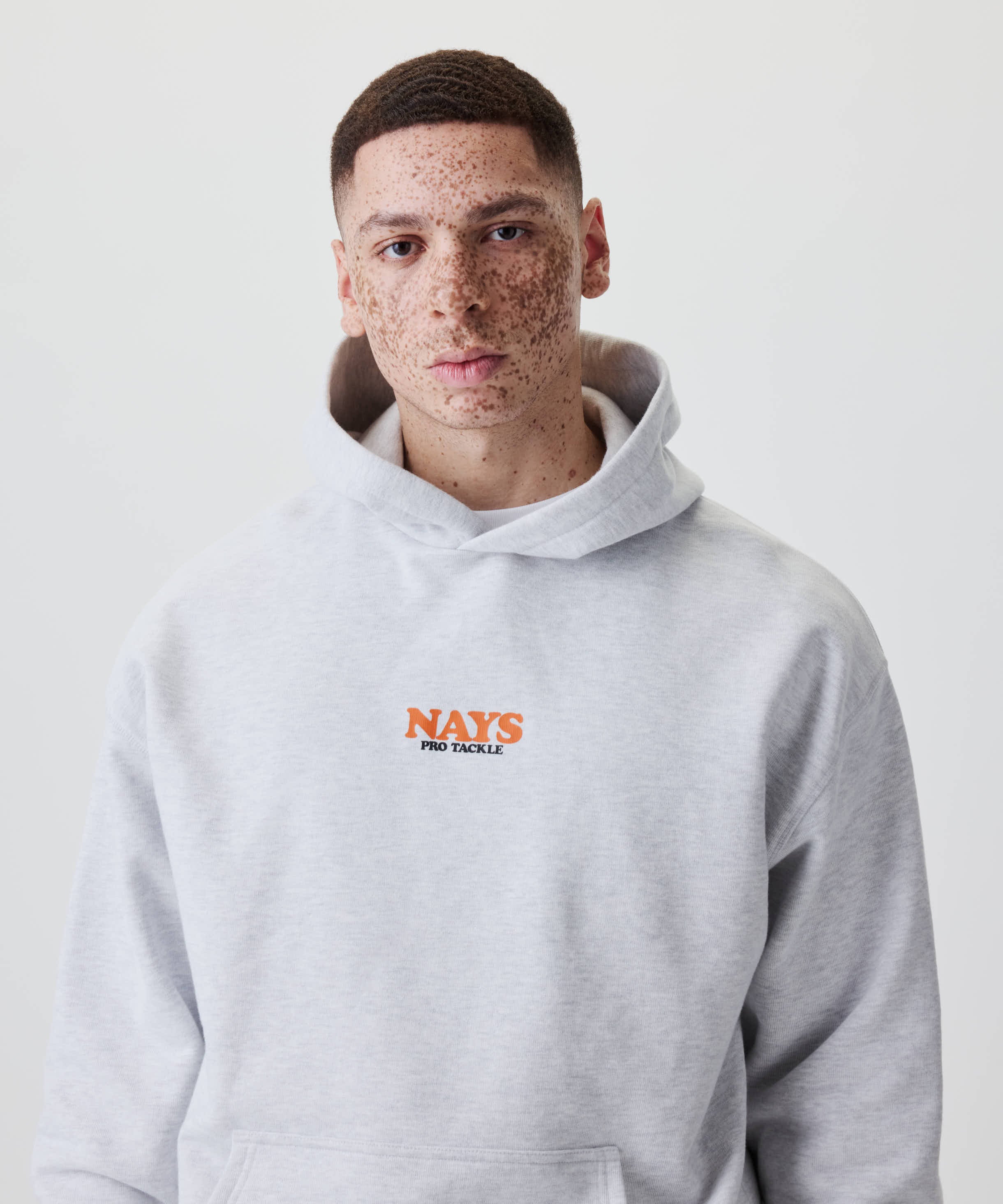 Junger Mann trägt den Nays College Print Hoodie mit NAYS PRO TACKLE-Logo auf der Brust, ideal für Alltag und Freizeit.