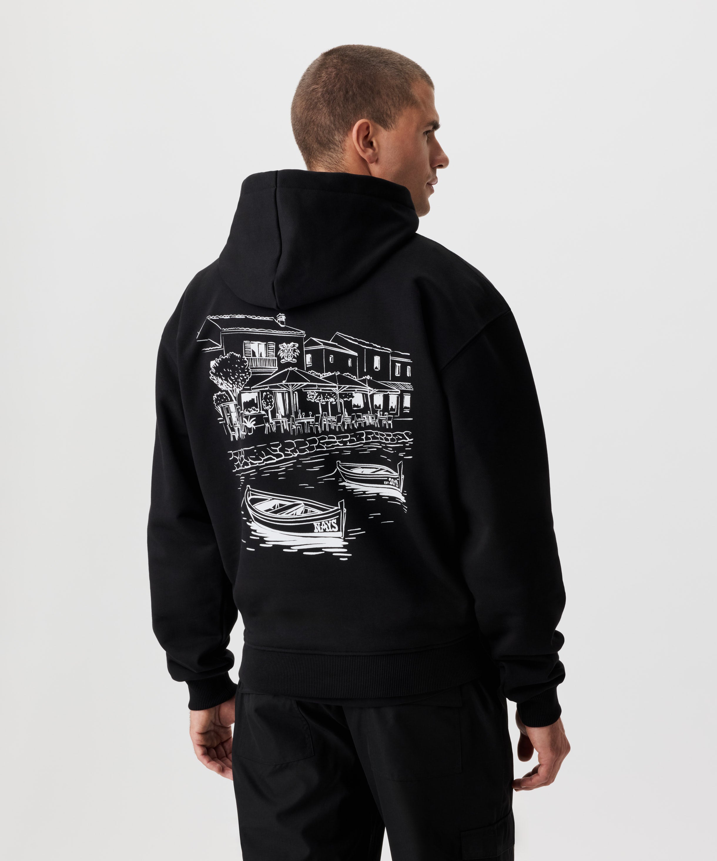 Rückansicht Mann im schwarzen Kapuzen Sweatshirt. Das Sweatshirt hat einen auffälligen Druck in weiß.