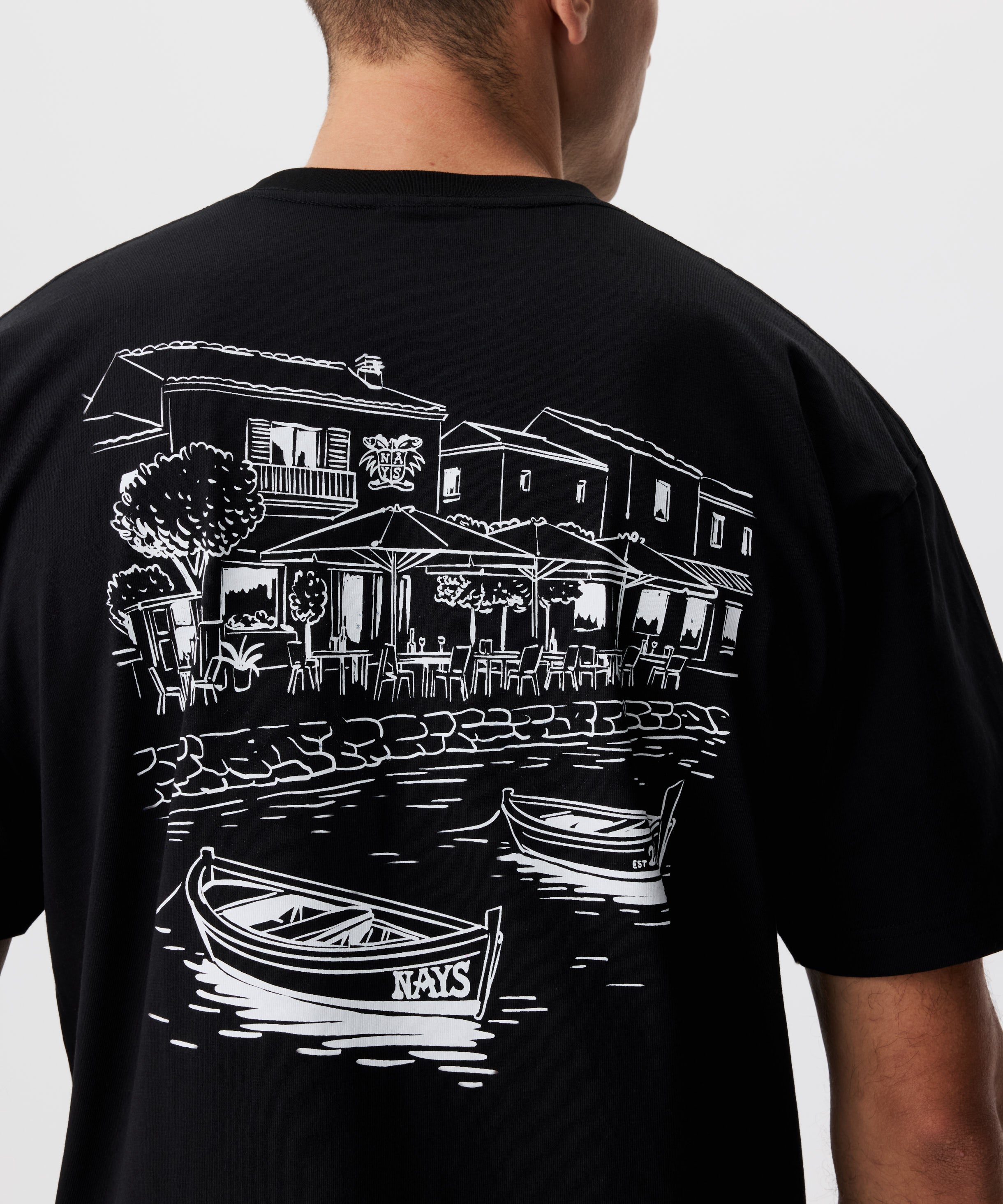 Rückansicht Mann im schwarzen T-Shirt. Das T-Shirt hat einen auffälligen Druck in weiß.