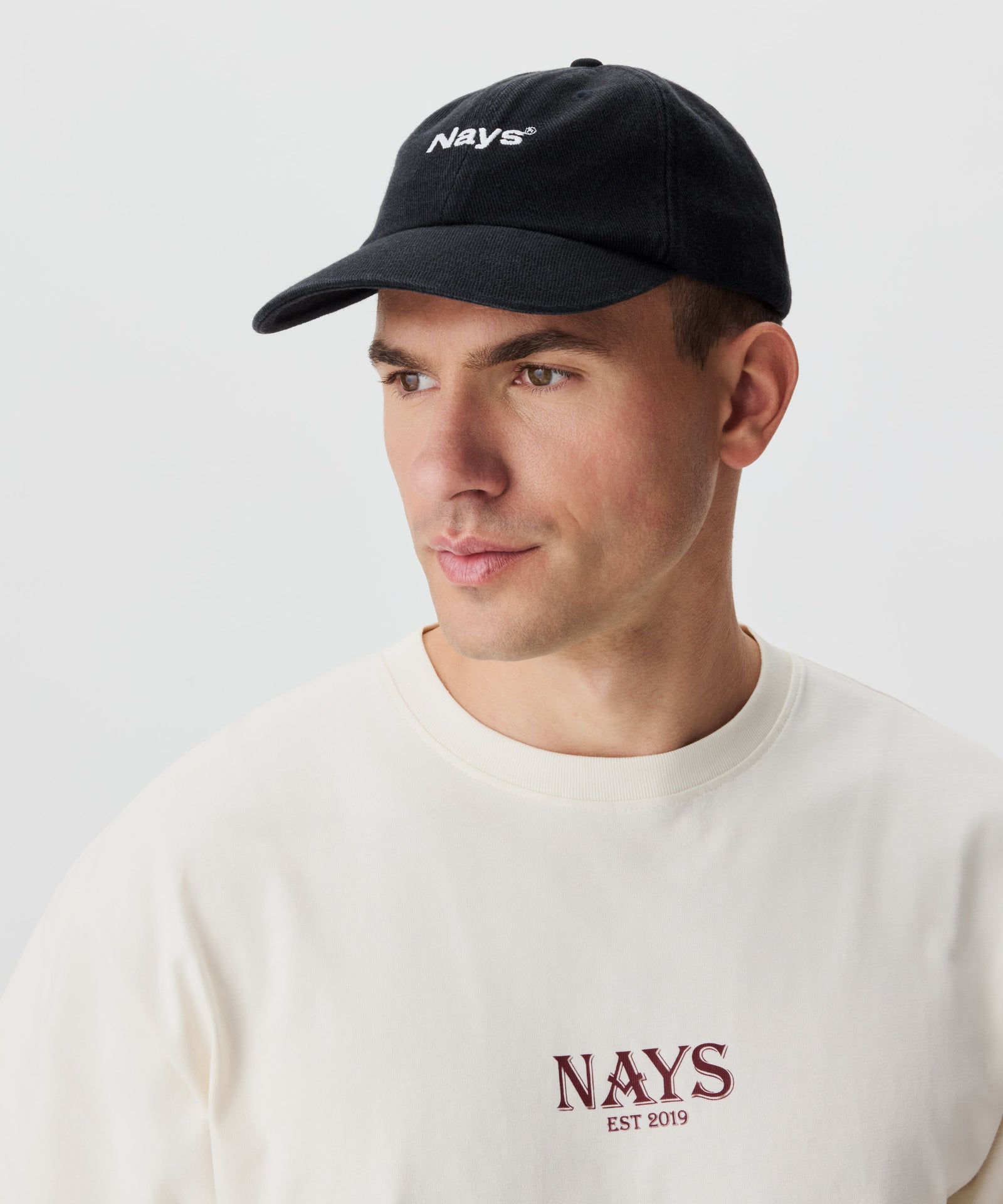 Frontansicht Mann mit dunkelgrauer Cap und Nays-Logo-Schriftzug vorne.