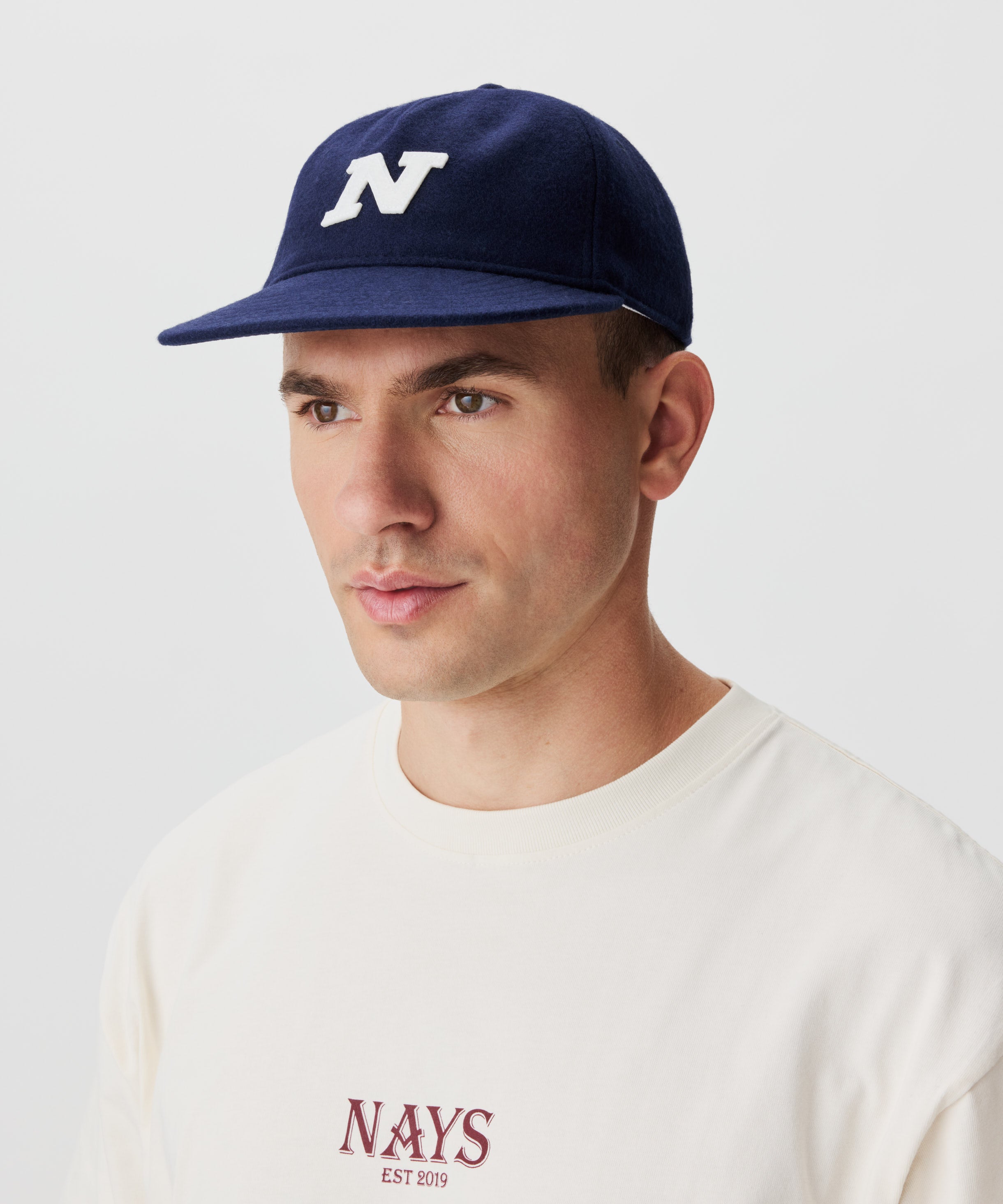 Frontansicht Mann mit blauer Cap und großem N-Logo vorne.