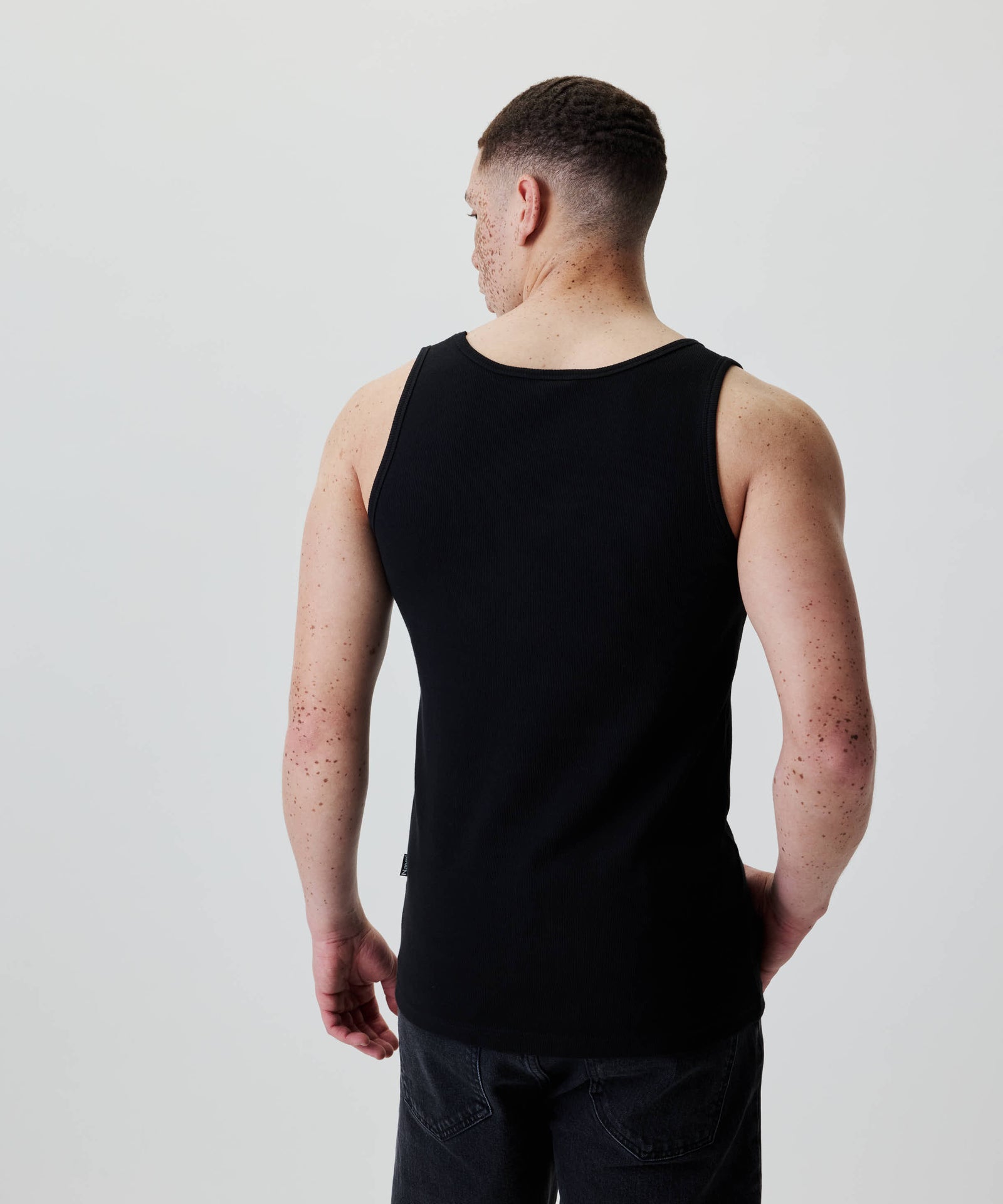Ein junger Mann trägt das Nays Classic Rib Tank Top, zeigt das gerippte Baumwollmaterial und den schlichten Schnitt für bequeme Alltagslooks.