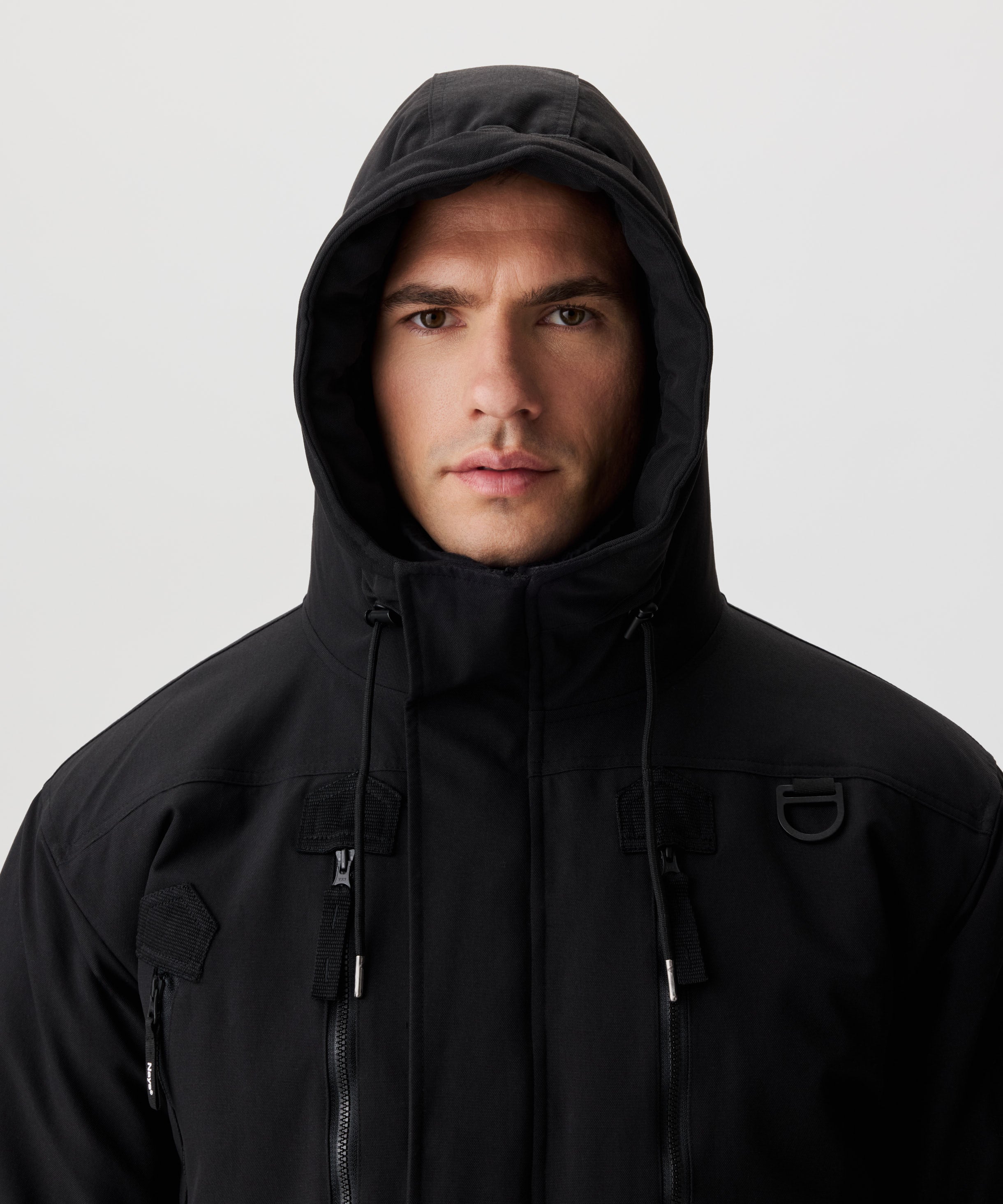 Frontansicht Mann im schwarzen Winterparka und aufgesetzter Kapuze.