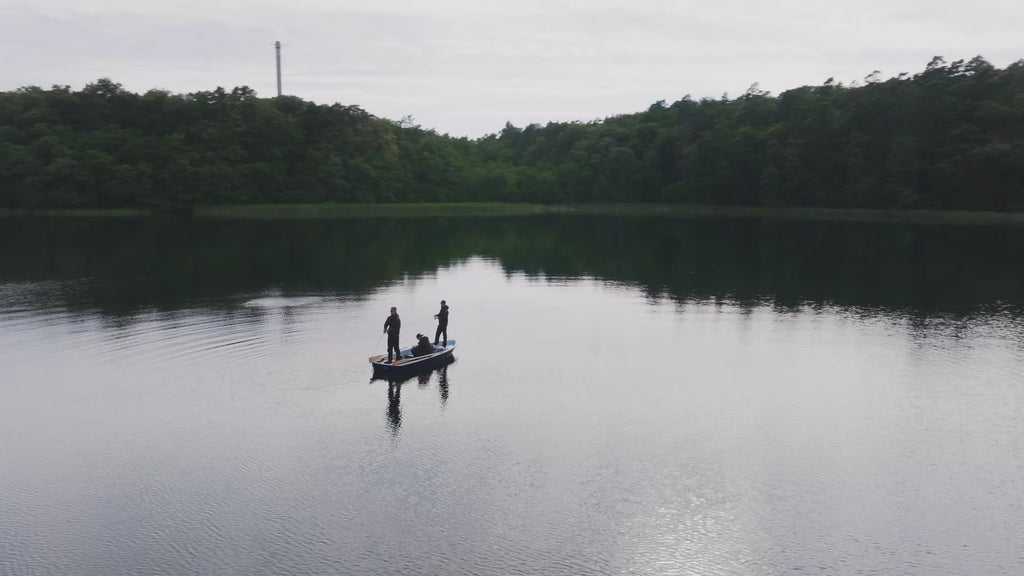 Nays Video Startseite. Aufnahme einer Drohne über Wald und See.