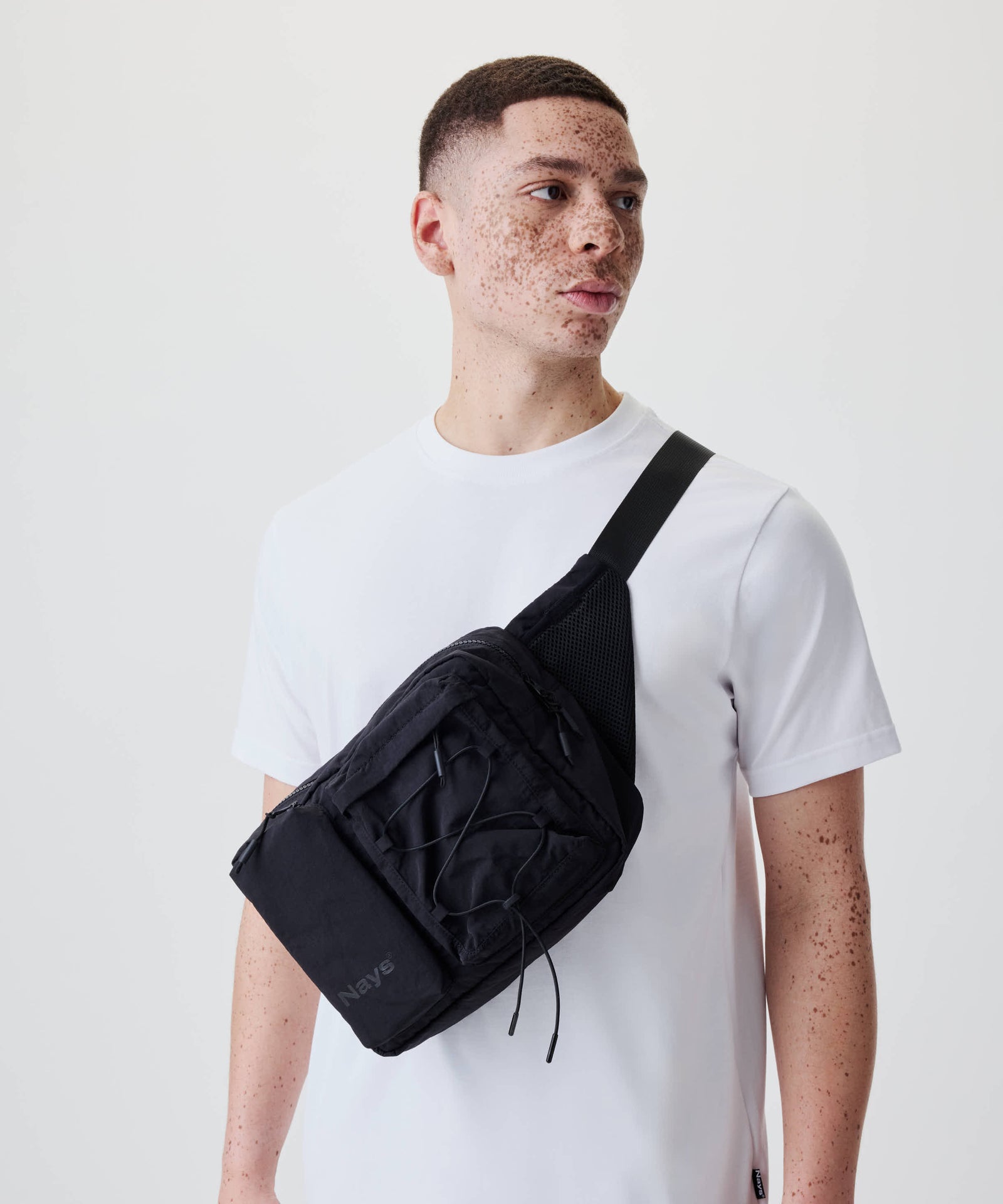 Person trägt die Nays Utility Cross Body Bag 2.0 mit mehreren Reißverschlussfächern und verstellbaren Gurten, ideal für Alltag und Reisen.