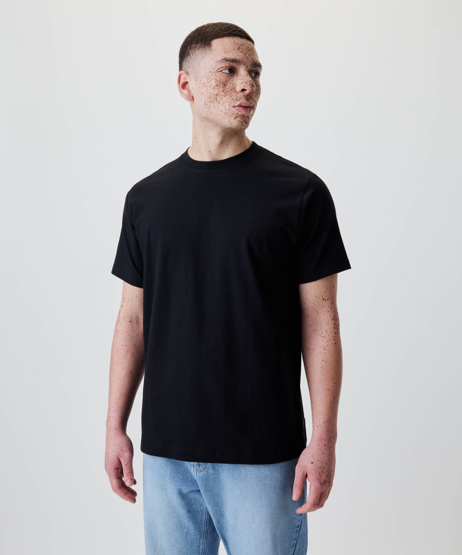 Junge Person trägt das Nays Classic Regular Flag Tee mit regulärer Passform, ohne überschnittene Schultern, für eine klare Silhouette.