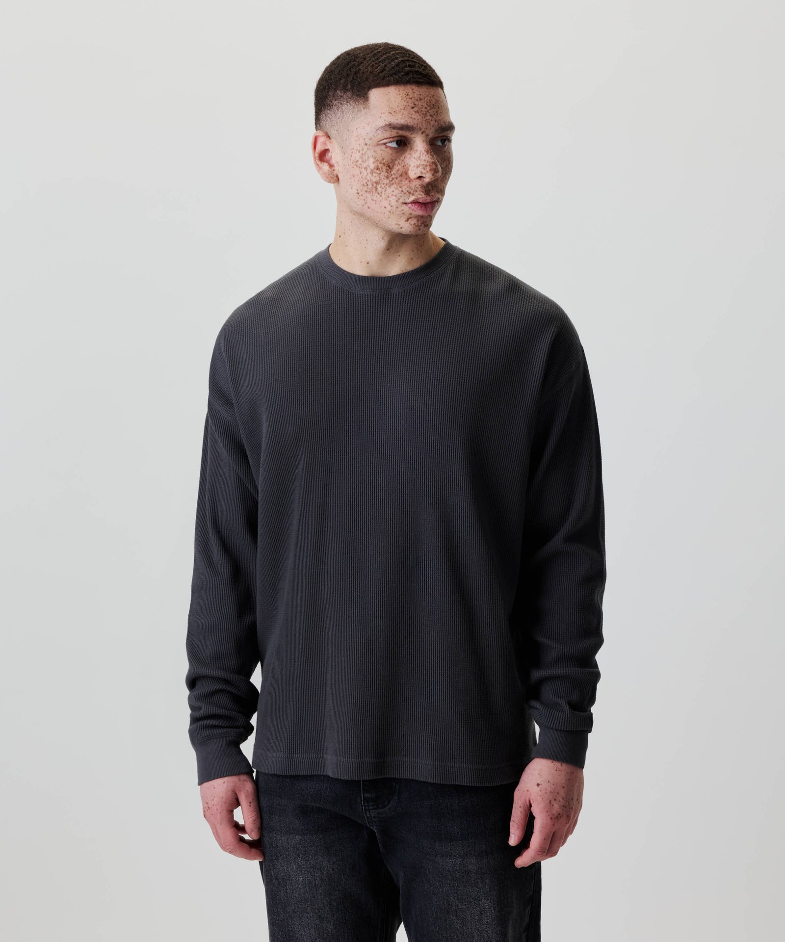 Junger Mann trägt Nays Classic Waffle Longsleeve in Anthrazit, aus 100 % Baumwolle, mit dezenten Naht-Details und entspanntem Schnitt.