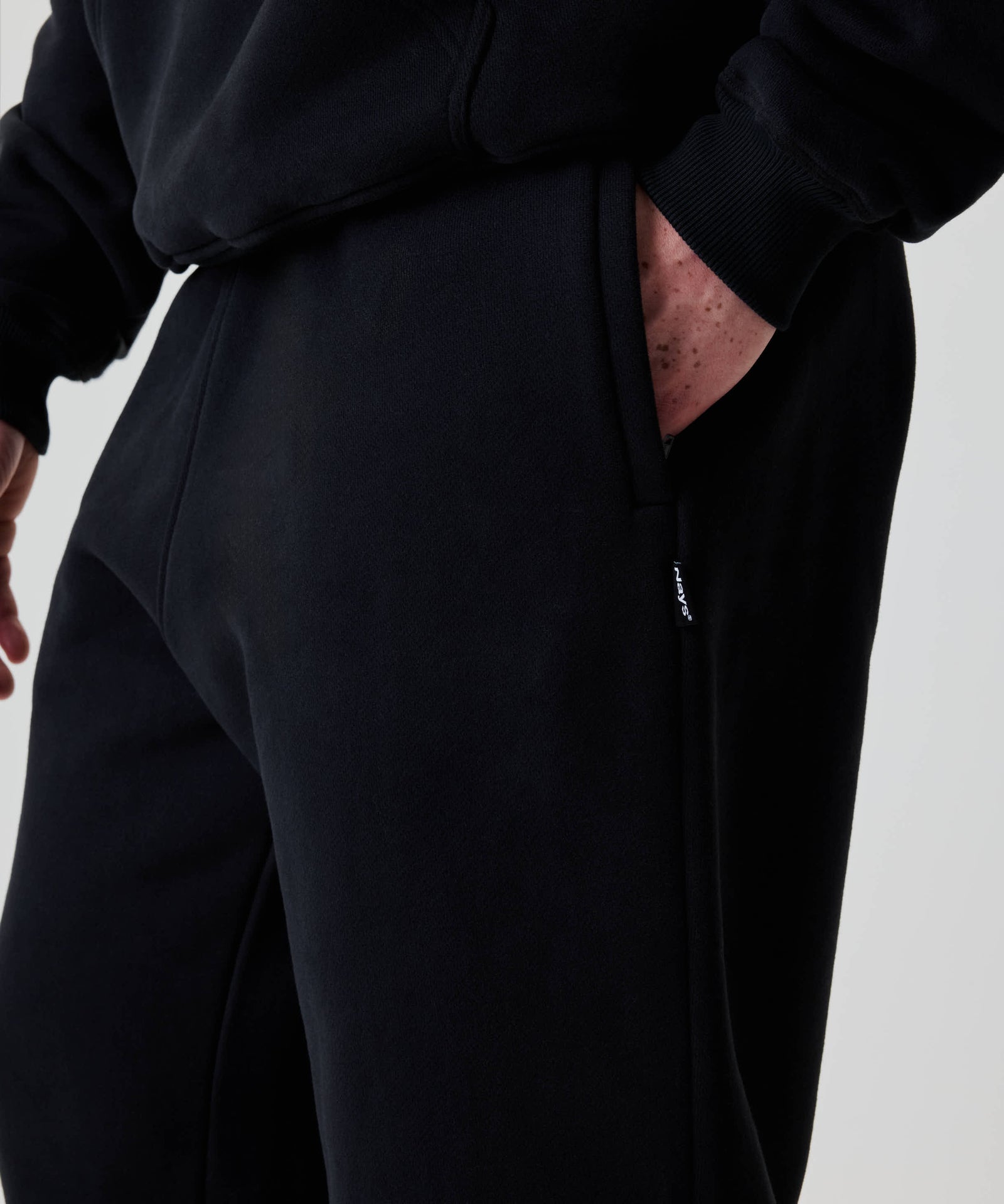 Nahaufnahme der Nays Baggy Sweatpants, zeigt eine Hand in der Seitentasche. Die Jogginghose bietet Komfort und einen lässigen Look.