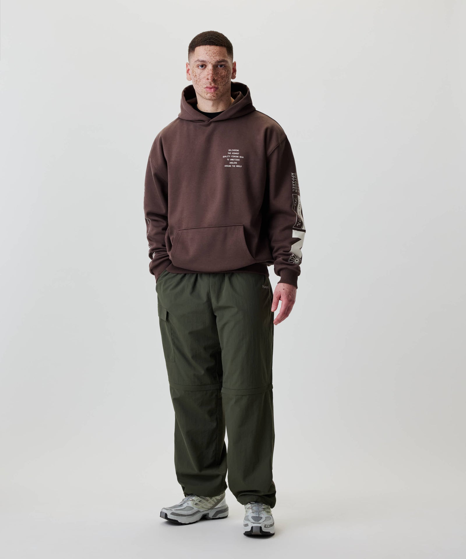 Ein junger Mann trägt den Nays Quote Hoodie in Braun, locker geschnitten mit weißen Grafiken, ideal für den Alltag und komfortabel durch Fleece-Innenseite.