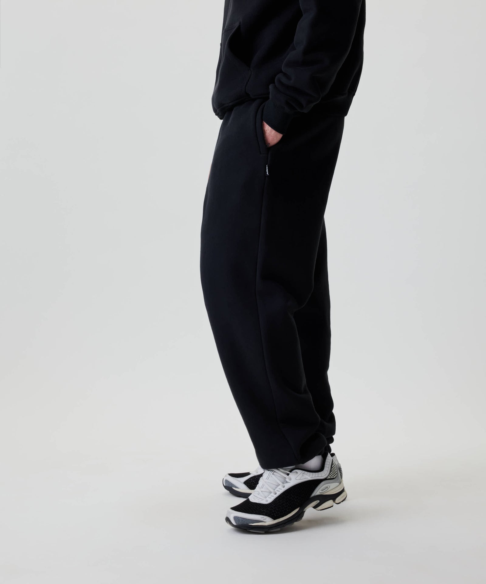 Nays Baggy Sweatpants in Schwarz, locker sitzend mit praktischen YKK Zipper-Taschen. Trägt eine dezente Stickerei auf der Rückseite für eleganten Alltagskomfort.