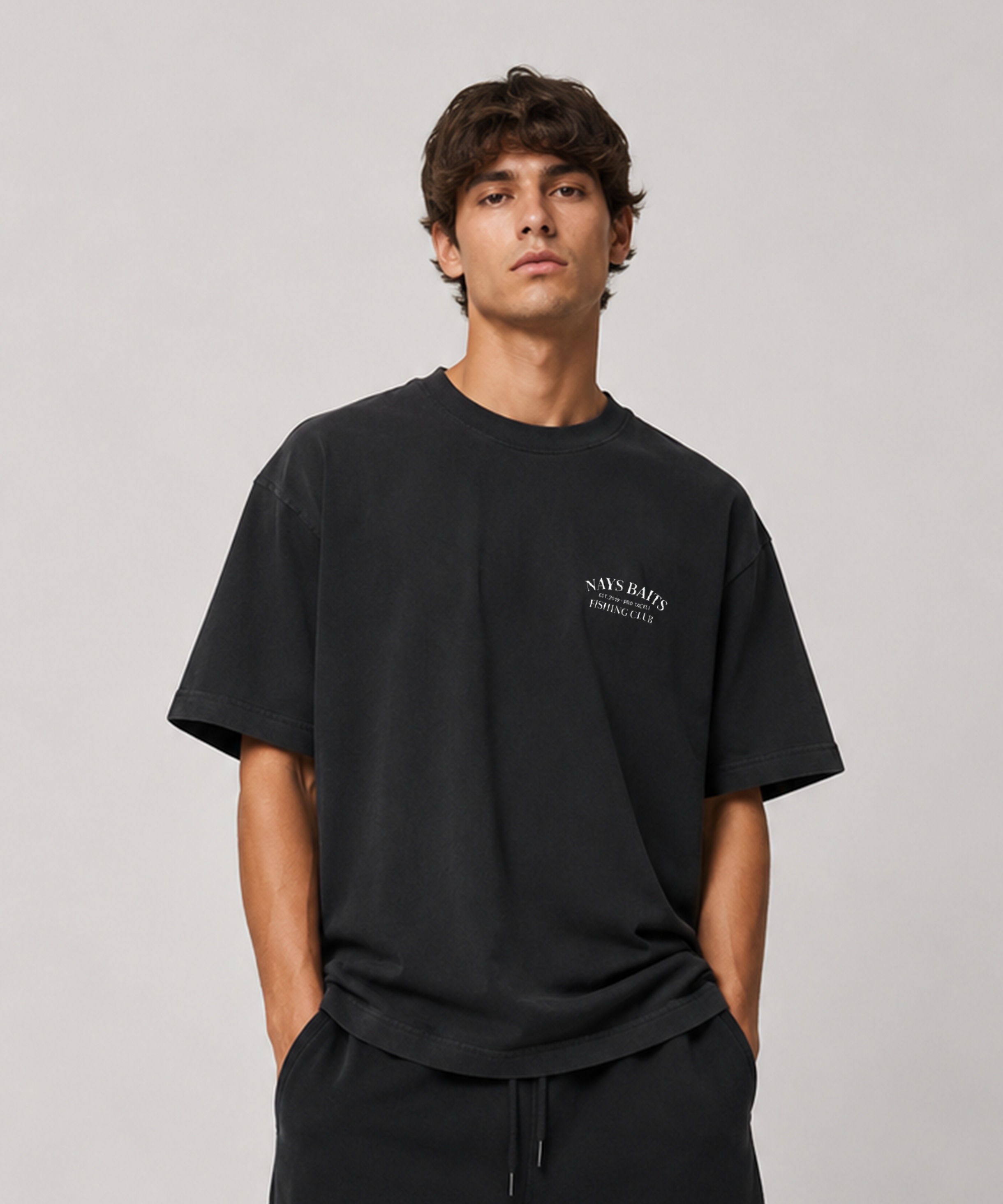 Model trägt Nays Baits Fishing Club T-Shirt in Schwarz – Vorderansicht mit weißem Logo-Brustprint.
