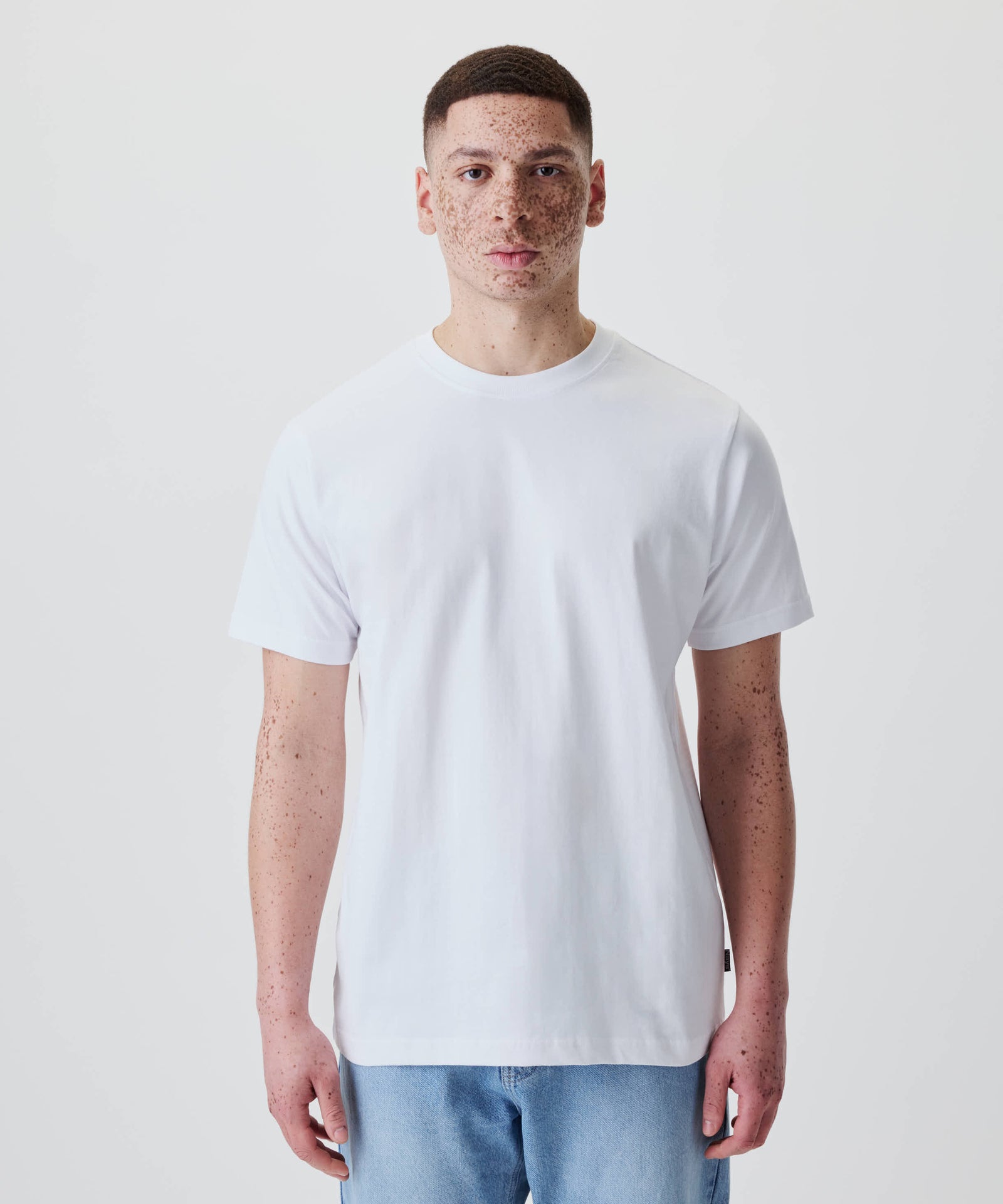 Person trägt das Nays Classic Regular Flag Tee, ein weißes, schlichtes T-Shirt im Regular-Fit, perfekt für einen klassischen Look im Alltag.