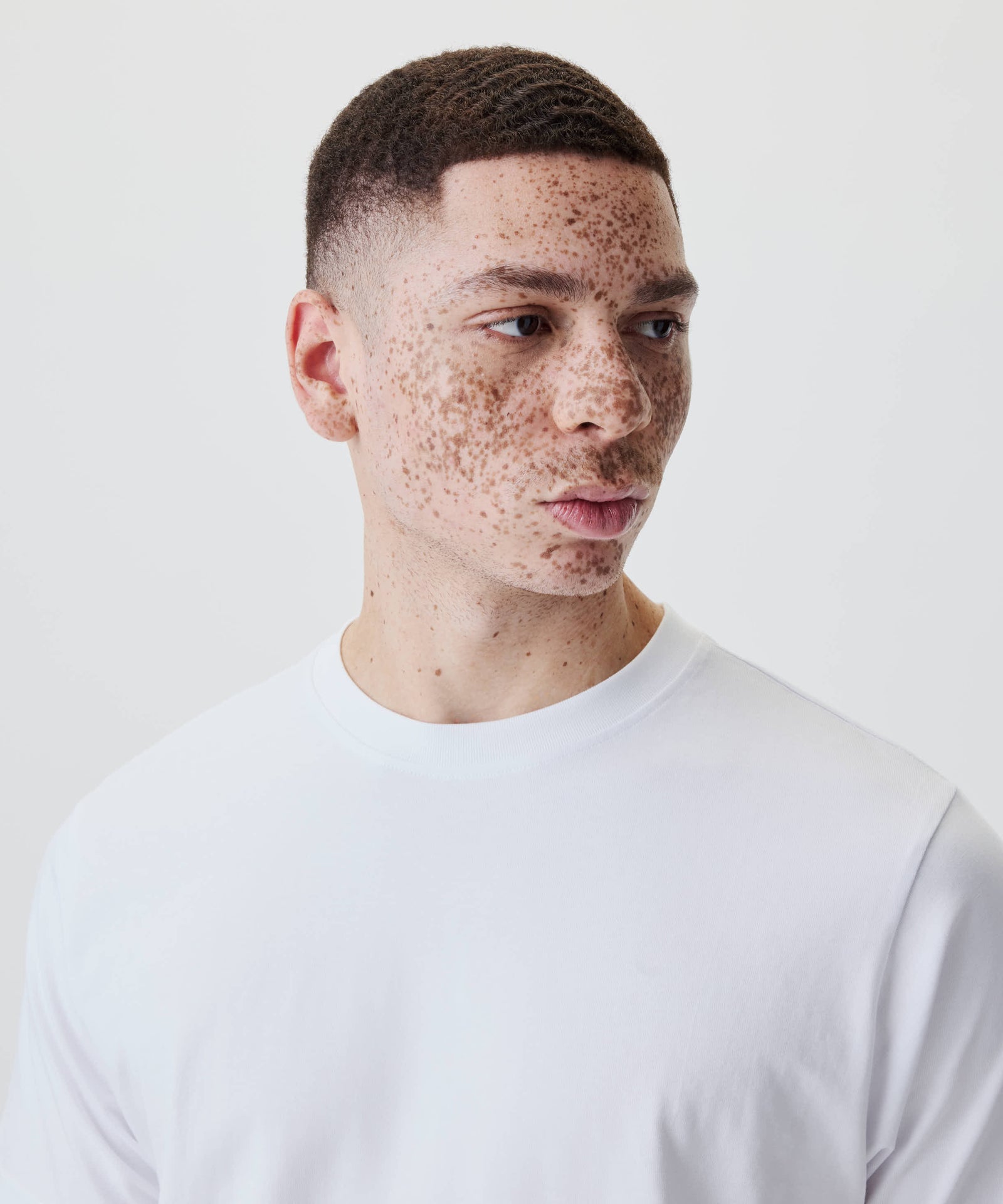 Person mit kurzen Haaren und neutralem Ausdruck trägt das Nays Classic Regular Flag Tee, ein vielseitiges, klassisch geschnittenes T-Shirt mit cleaner Silhouette.