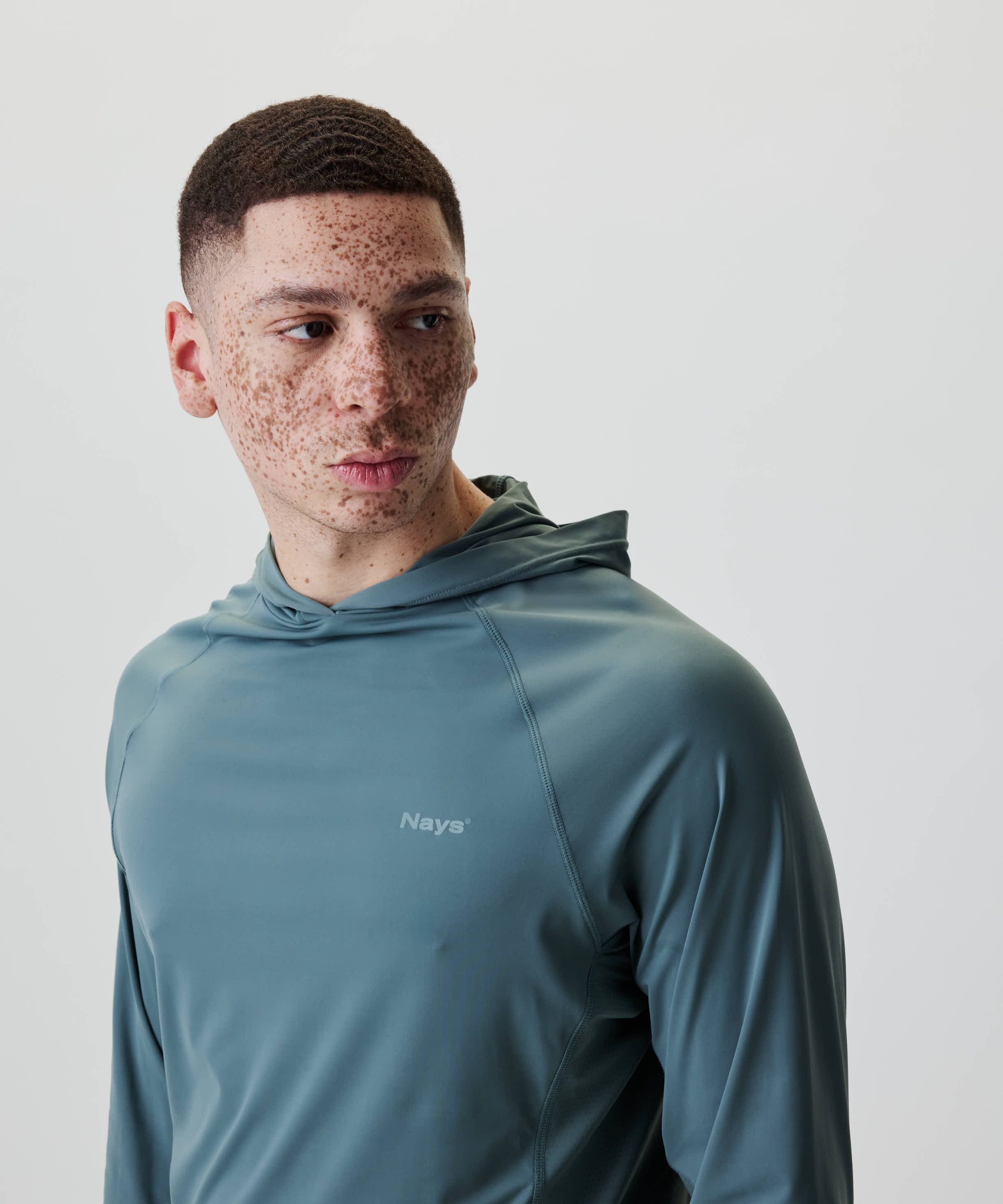 Junger Mann trägt Nays UV 50+ Hooded Longsleeve mit Raglanärmeln und Kapuze, ideal für Sonnenschutz bei Aktivitäten, leicht und funktional gestaltet.