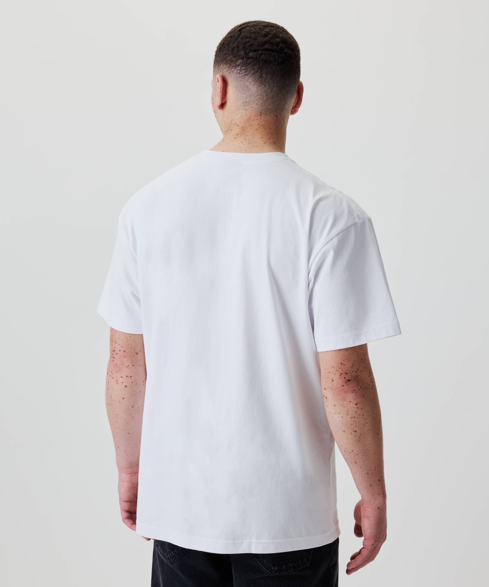 Person von hinten in einem Nays Loose Fit Chest Print Tee mit kurzen Ärmeln, das einen lässigen, oversized Look bietet.